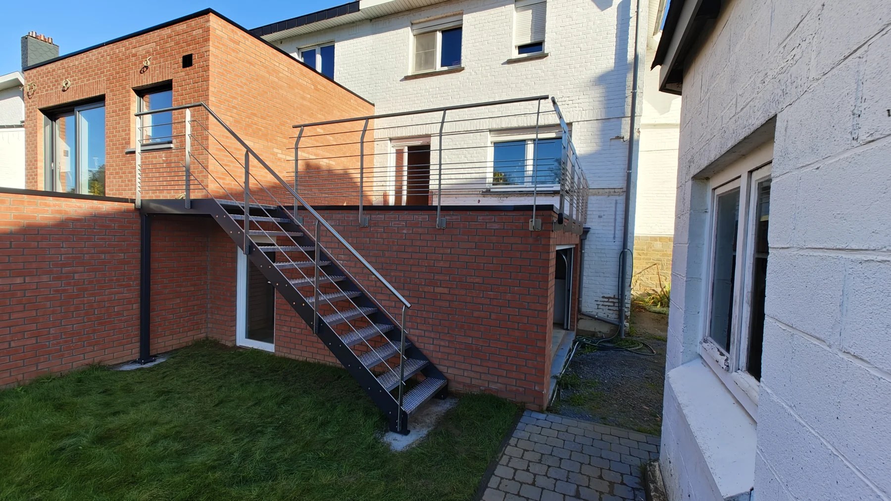 Escalier métallique extérieur reliant un jardin et une terrasse