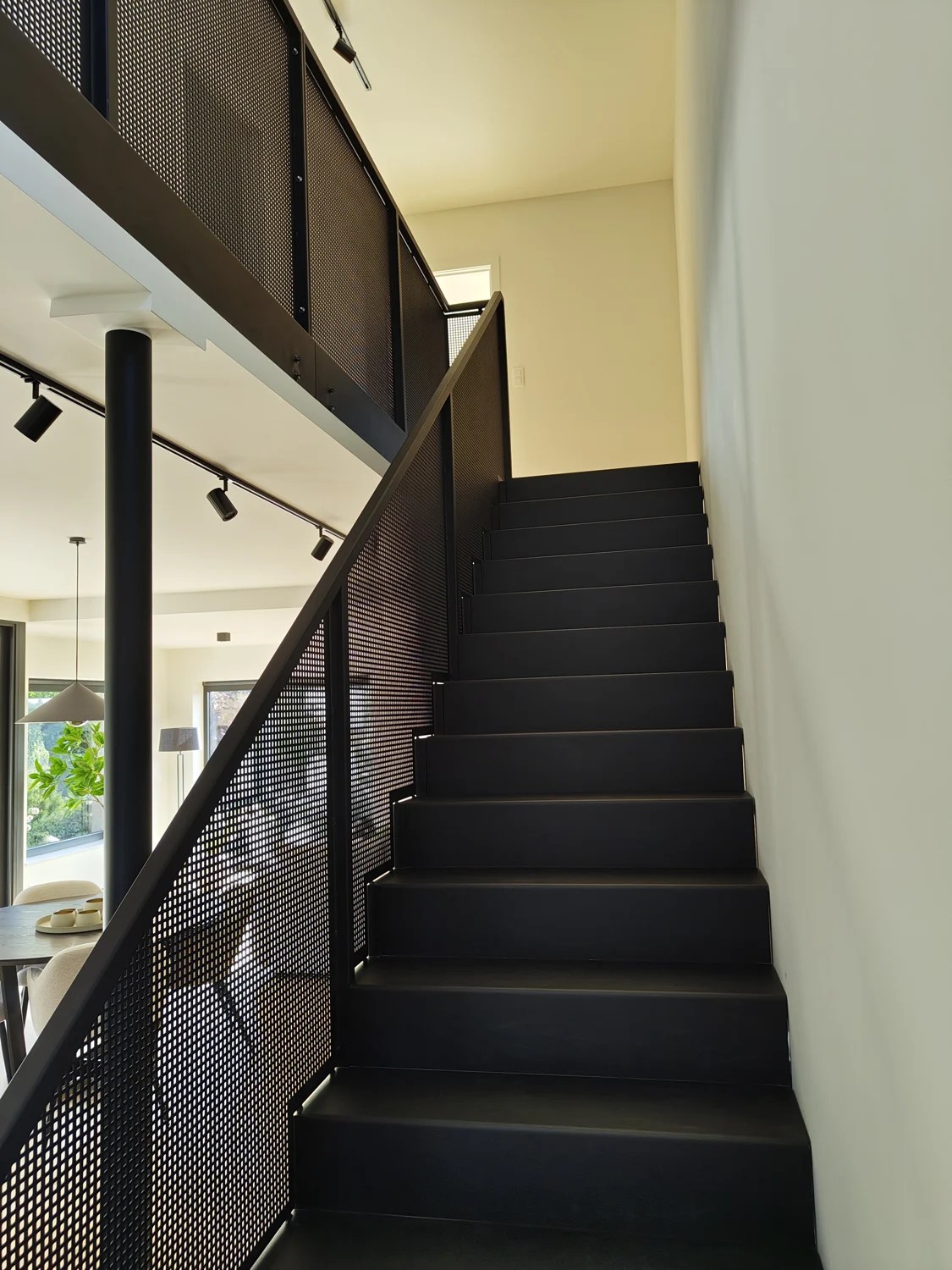 Vue depuis le pied de l’escalier noir et de son garde-corps perforé