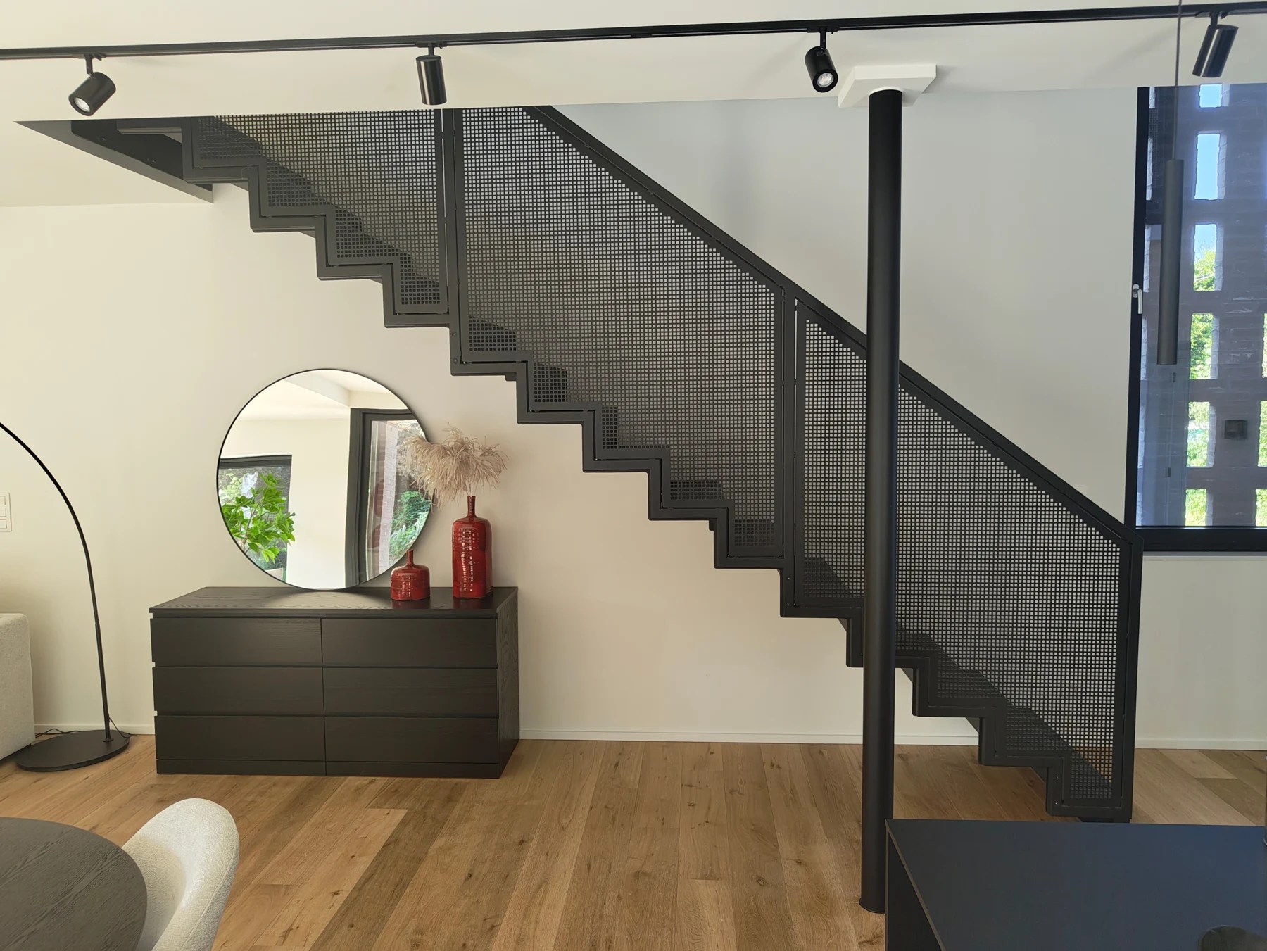 Escalier noir à garde-corps perforé dans un intérieur aménagé