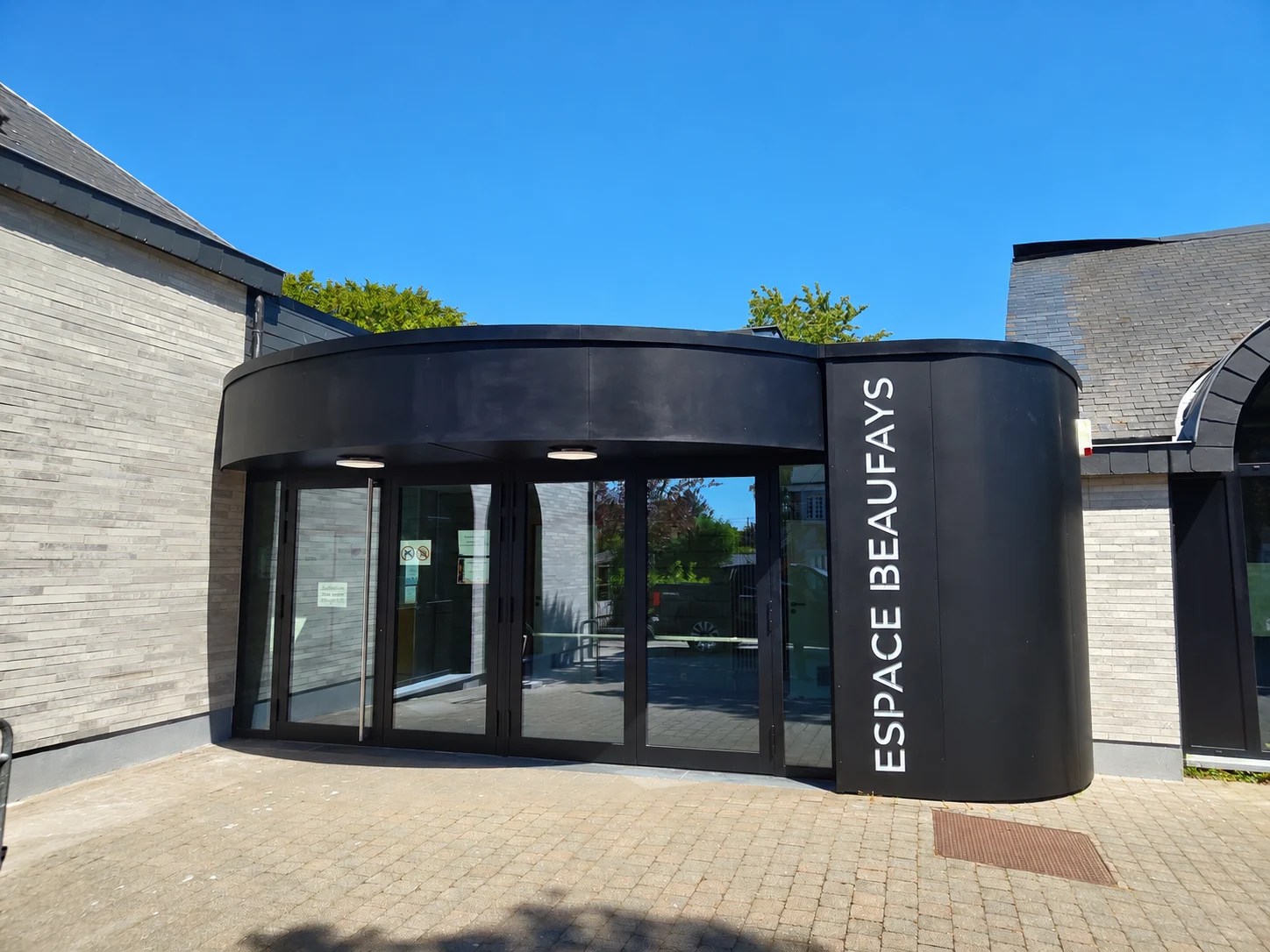 Habillage métallique noir à lignes courbes de l’entrée de l’Espace Beaufays